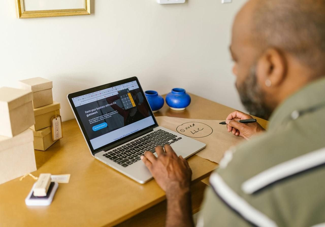 A man sitting at a desk in front of a laptop, searching for tips on how to write an about us page.